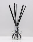 Crisp uplifting aromas of wild meadow flowers and morning dew, nestled on a bed of sweet amber Luxury long lasting Bouquet reed diffuser with natural black sticks in a 100ml clear glass bottle with silver top.
