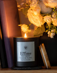 Candle labeled 'Effime Home Fragrance Coconut Lime' with a vase of flowers in the background
