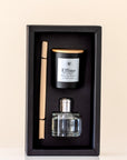 Perfume set with a bottle, candle, and diffuser stick in a black box on a beige background