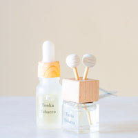 Perfect for slow quiet moments of reflection Luxury long lasting Tonka Tobacco Car diffuser with natural wooden sticks in a clear glass bottle with wooden top.
