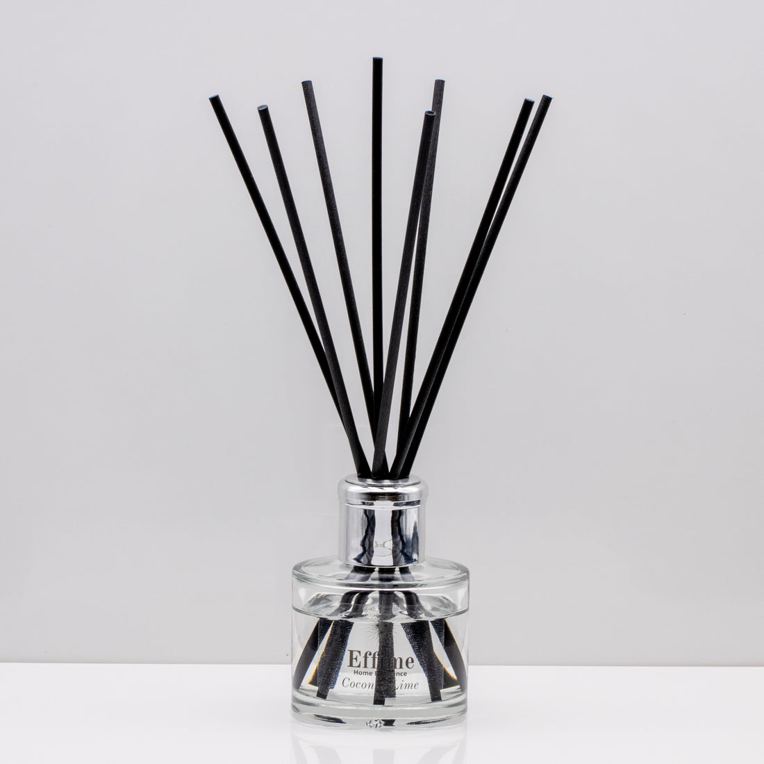 Creamy coconut, zesty lime, sweet orange and crisp apple Luxury long lasting Coconut Lime reed diffuser with natural black sticks in a 100ml clear glass bottle with silver top