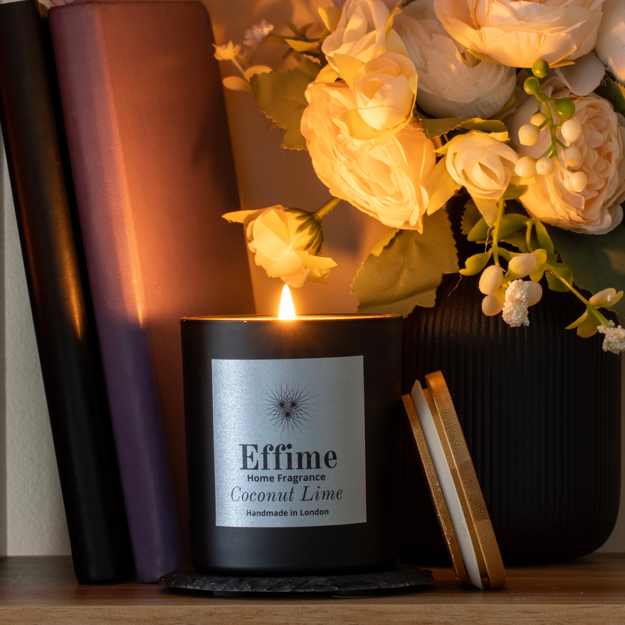 Candle labeled 'Effime Home Fragrance Coconut Lime' with a vase of flowers in the background