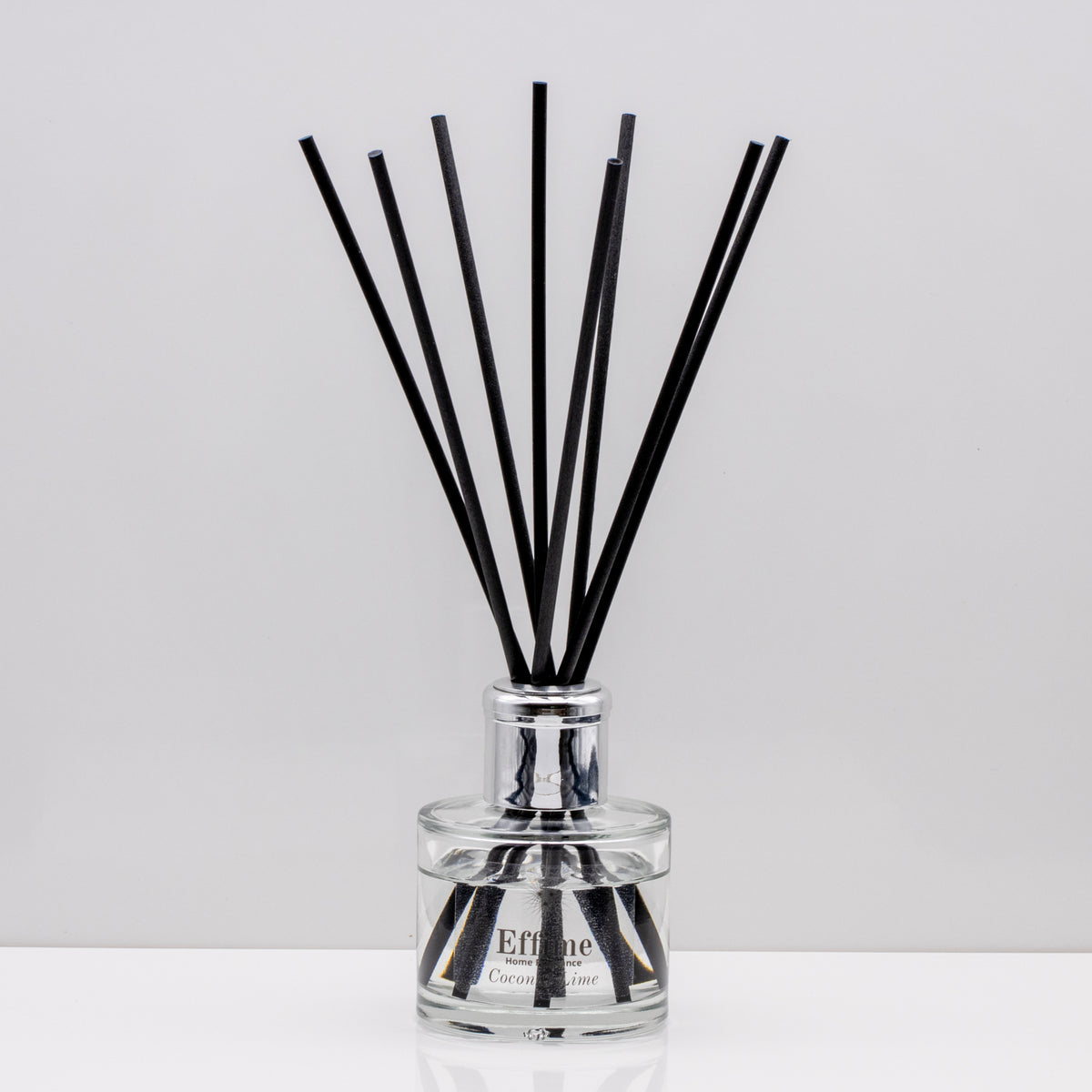 Creamy coconut, zesty lime, sweet orange and crisp apple Luxury long lasting Coconut Lime reed diffuser with natural black sticks in a 100ml clear glass bottle with silver top