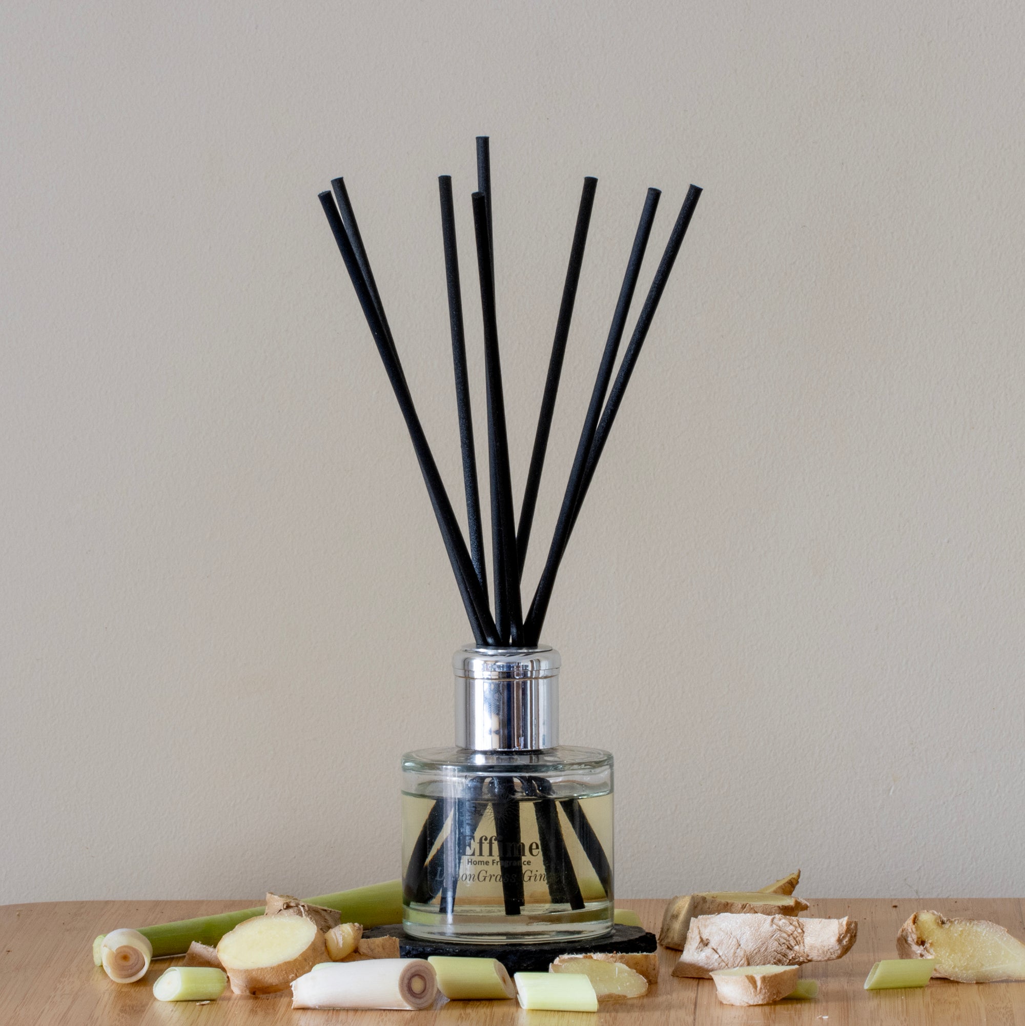 Reed diffuser with black sticks in a clear bottle on a wooden surface