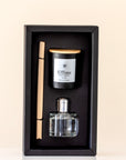 Aromatherapy set with diffuser, candle, and reed sticks in a black box on a beige background.
