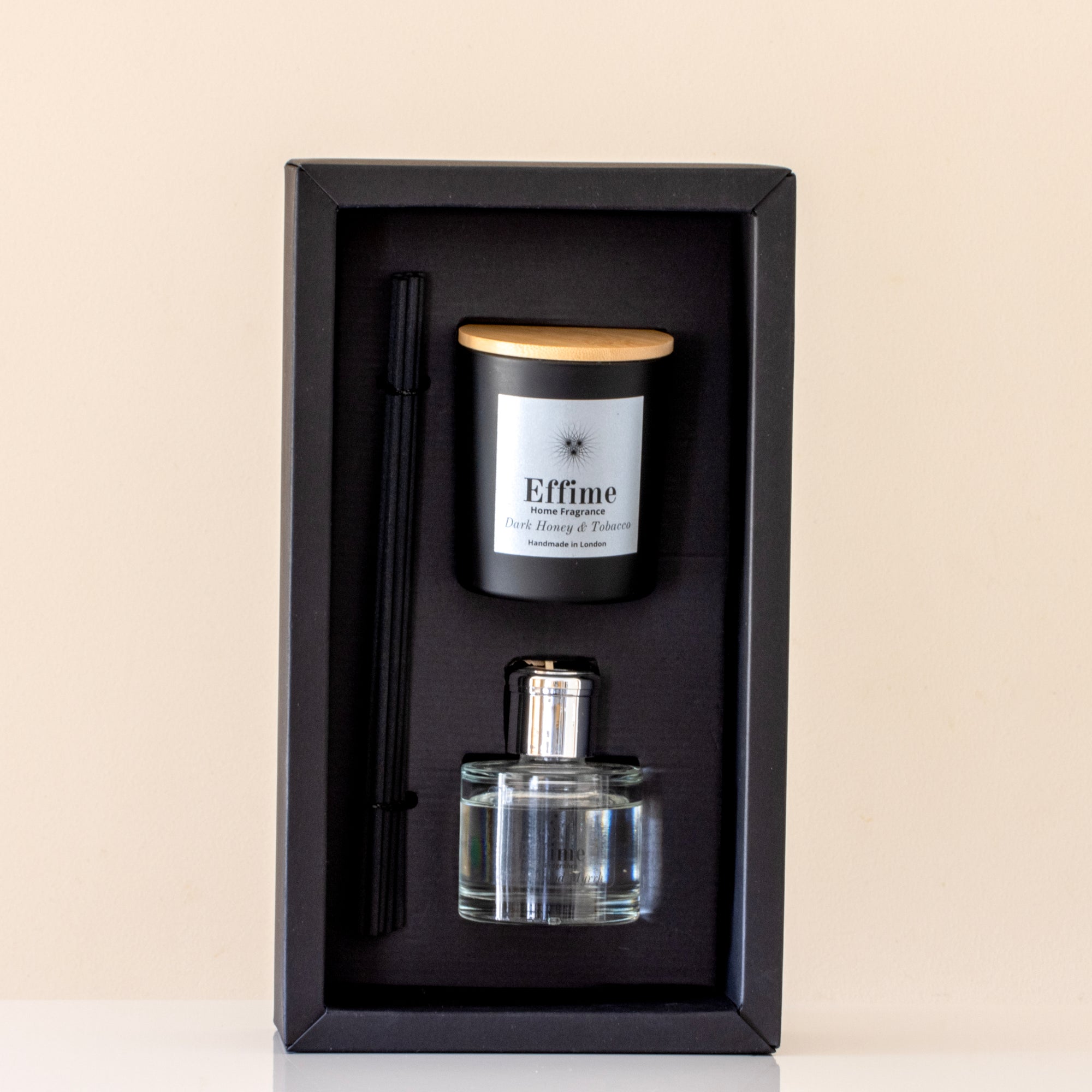 Candle and perfume set in a black box on a beige background