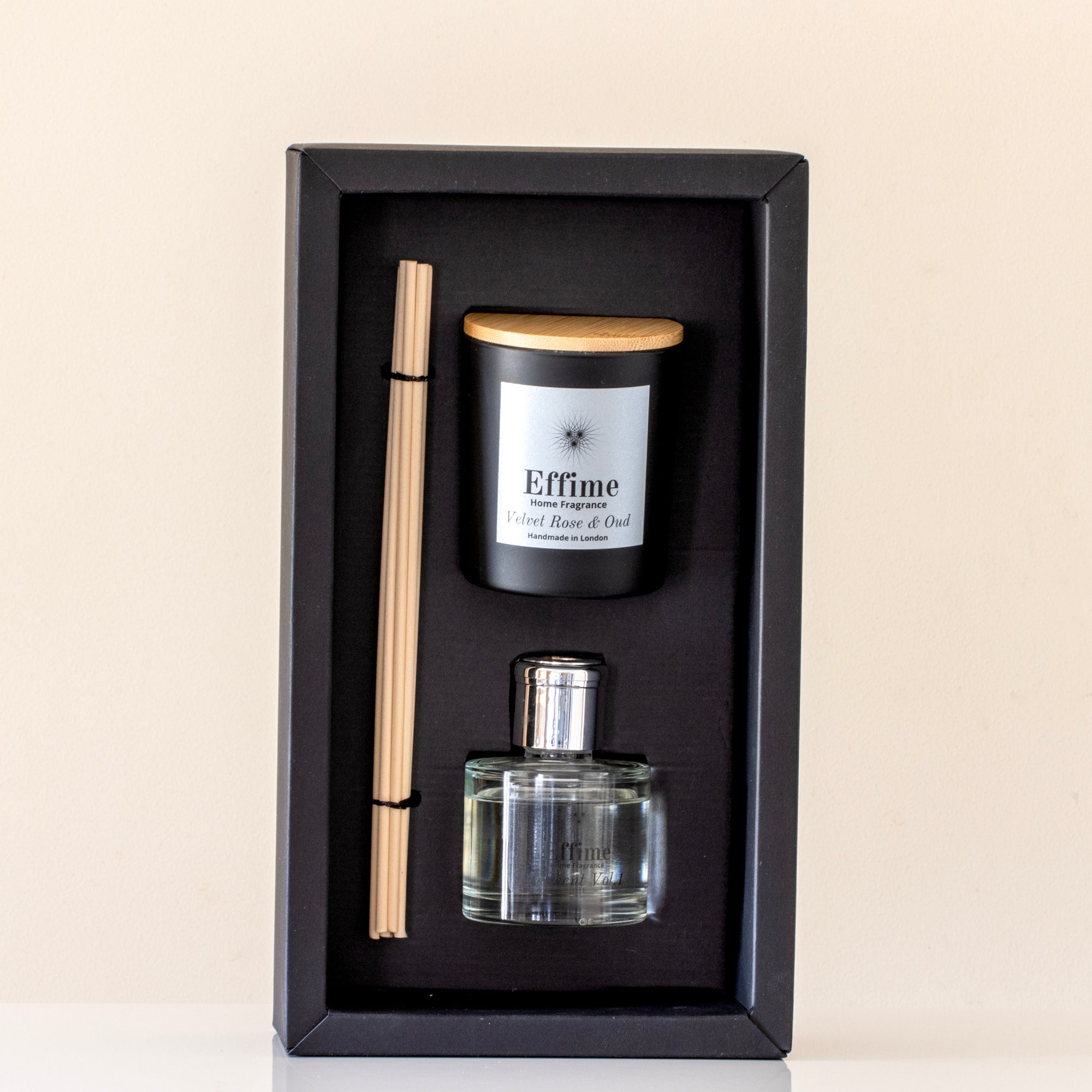 Set of diffuser bottle, candle, and reed sticks in a black box on a beige background