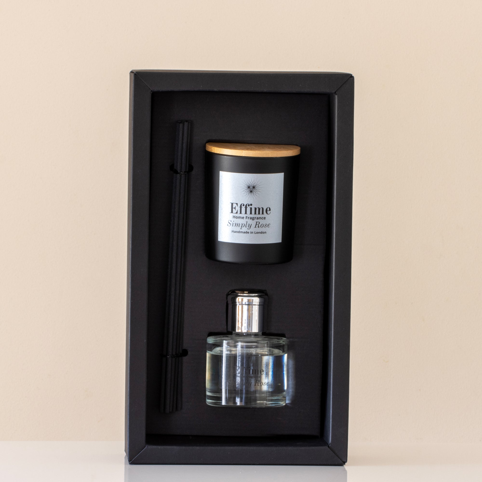 Candle and diffuser set in a black box on a beige background