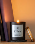 Candle with 'Effime' branding on a wooden surface with a soft background