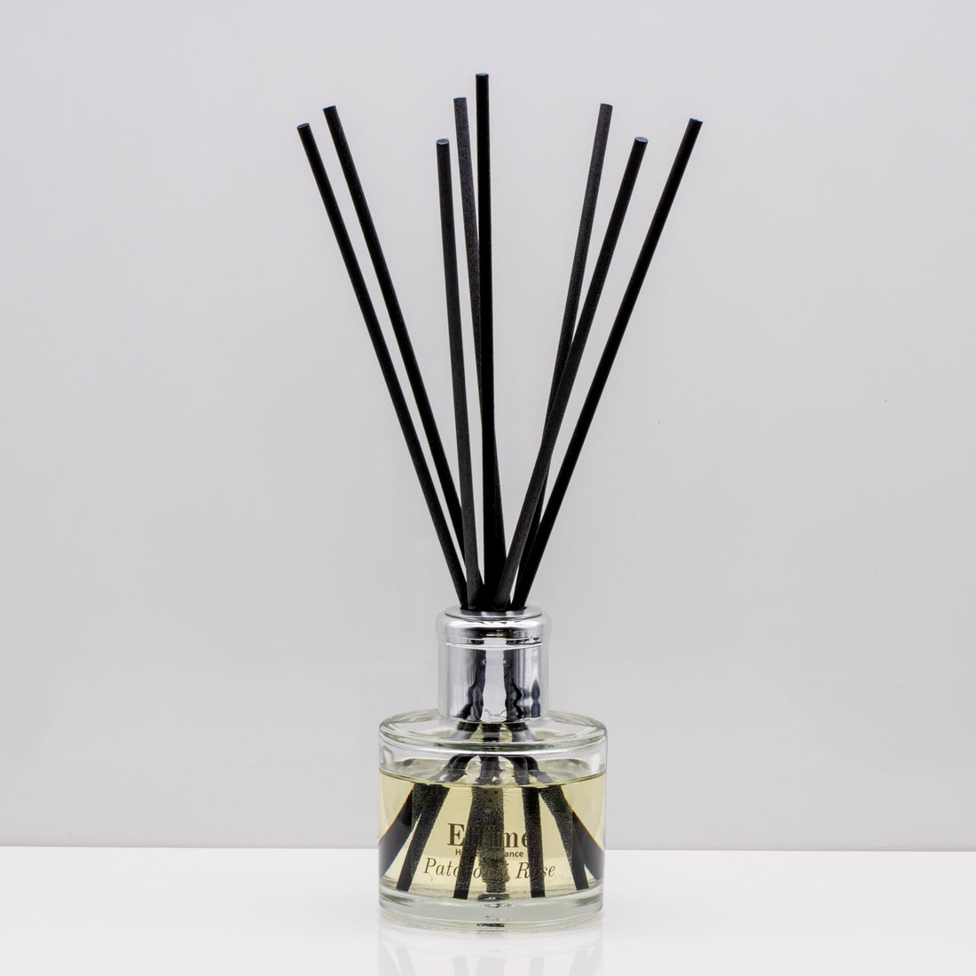 Rich decadent dark fruits with floral notes of rose, jasmine and fragrant patchouli Luxury long lasting Patchouli Rose reed diffuser with natural black sticks in a 100ml clear glass bottle with silver top.