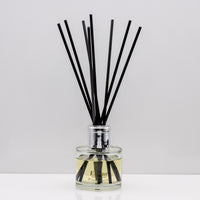 Wrap yourself in the comforting warmth of burnt wood and  vanilla Luxury long lasting Woody Vanilla reed diffuser with natural black sticks in a 100ml clear glass bottle with silver top.