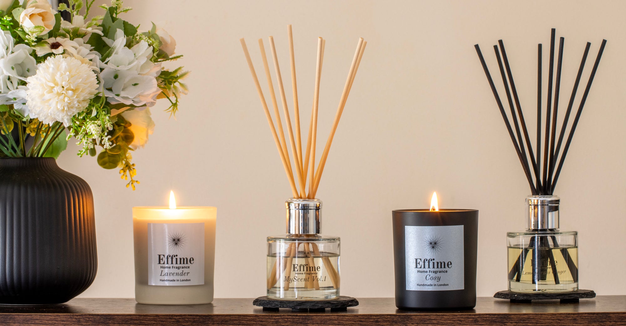 Decorative items including candles and diffusers on a wooden surface with a neutral background